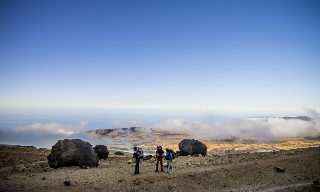 Wandelaars in een vulkanisch landschap met wolken op Tenerife.
