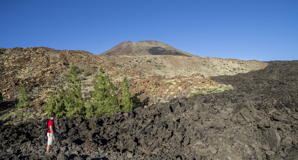 Persoon die wandelt in een vulkanisch landschap met de berg Teide op de achtergrond op Tenerife.