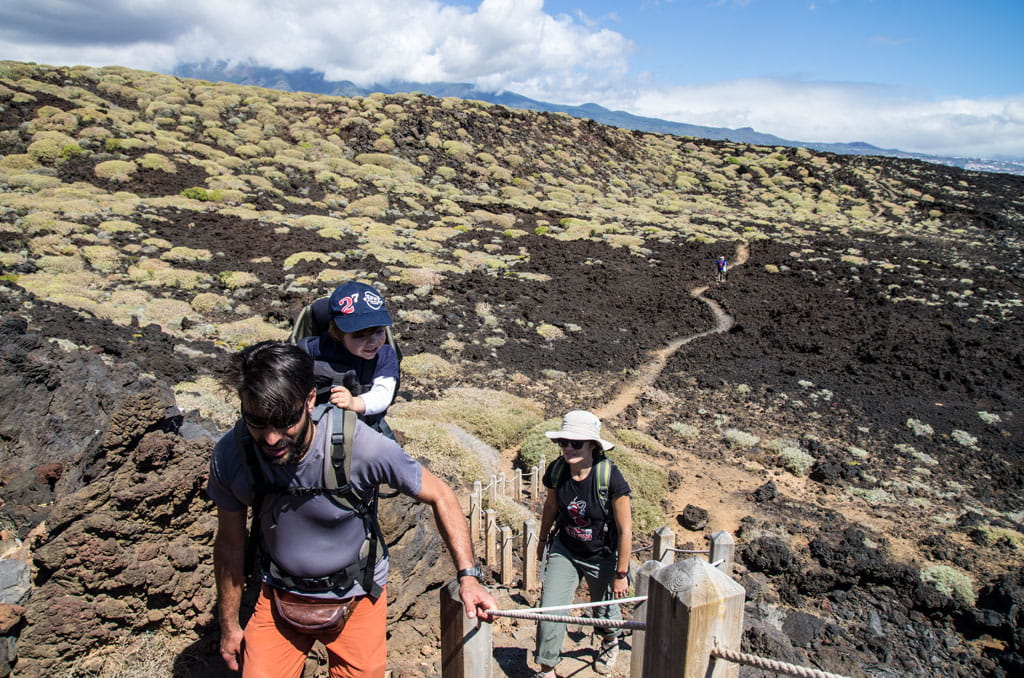 Mensen die over het vulkanische pad op Tenerife lopen onder deels bewolkte luchten.