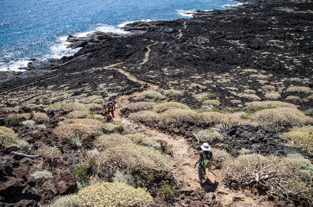 Mensen die wandelen op een vulkanisch pad nabij de kust op Tenerife.