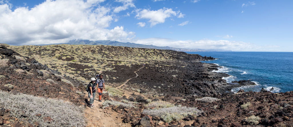Mensen die langs rotsachtige paden bij de kust lopen in Malpais de Güímar, Tenerife.