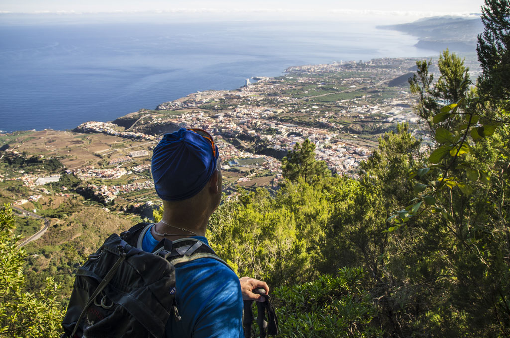 Persoon met rugzak die een kustlandschap observeert vanuit een uitkijkpunt op Tenerife.