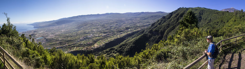 Panoramisch uitzicht op de Orotava-vallei op Tenerife vanaf een uitkijkpunt met een wandelaar.