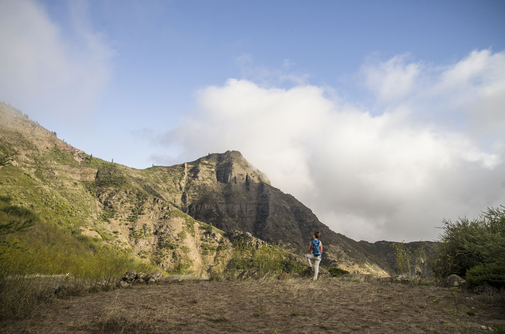 Persoon die voor bergen op Tenerife loopt onder deels bewolkte luchten.