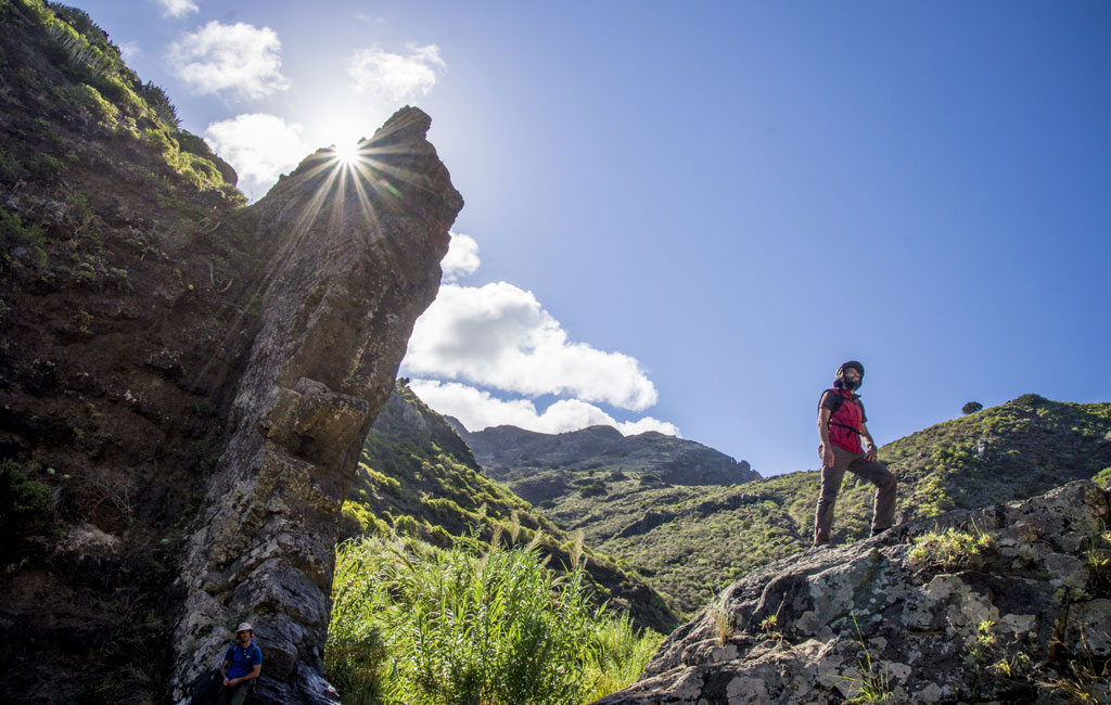 Persoon die wandelt in de Masca-ravijn, Tenerife, met de zon die achter hem schijnt.