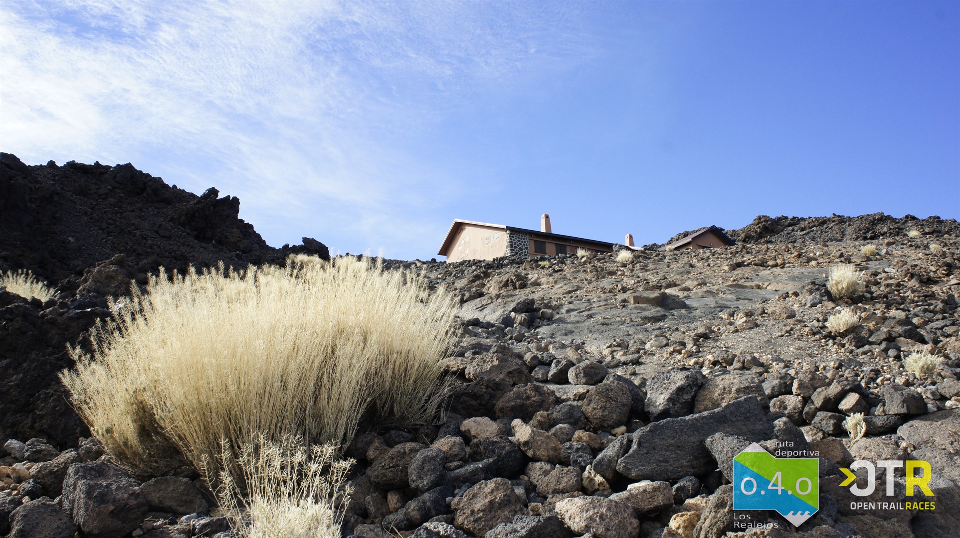 Rotsachtig landschap met gebouwen op El Teide, Tenerife, heldere lucht, OTR-logo zichtbaar.