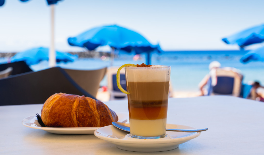 Barraquito-koffie en croissant aan zee op Tenerife.