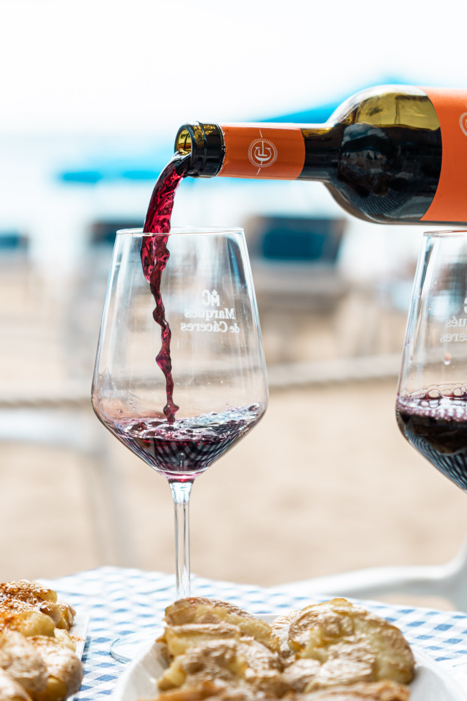 Rode wijn die in een glas met taarten op een strandtafel op Tenerife werd geschonken.