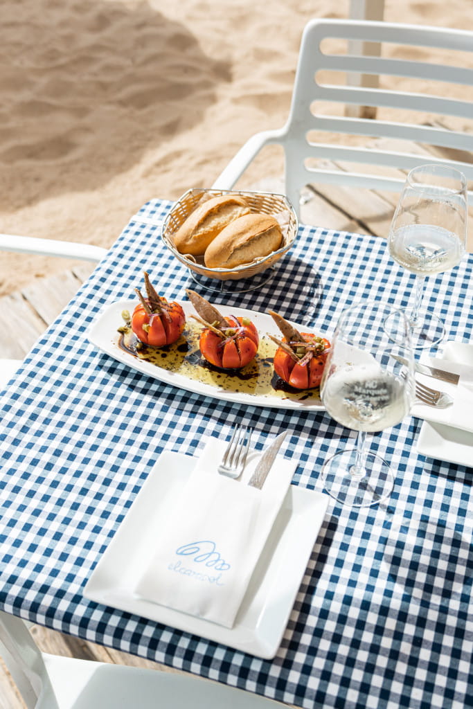 Tafel met gevulde tomaten, brood en een glas wijn voor het strand van El Ancla op Tenerife.
