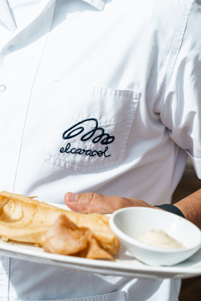 Ober in wit slakkenshirt draagt bord eten.