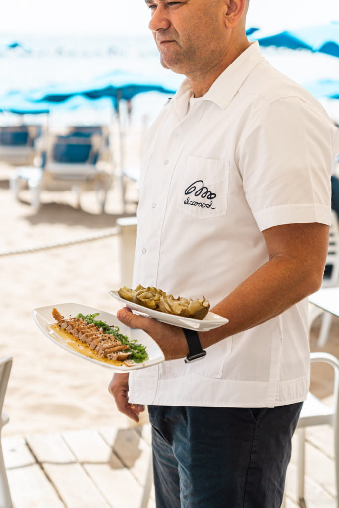 Persoon die borden met eten serveert op een strand op Tenerife.