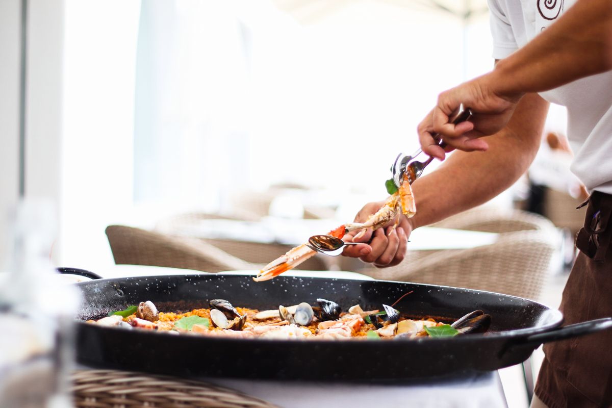 Persoon die zeevruchten serveert in een paella op een restaurantterras op Tenerife.