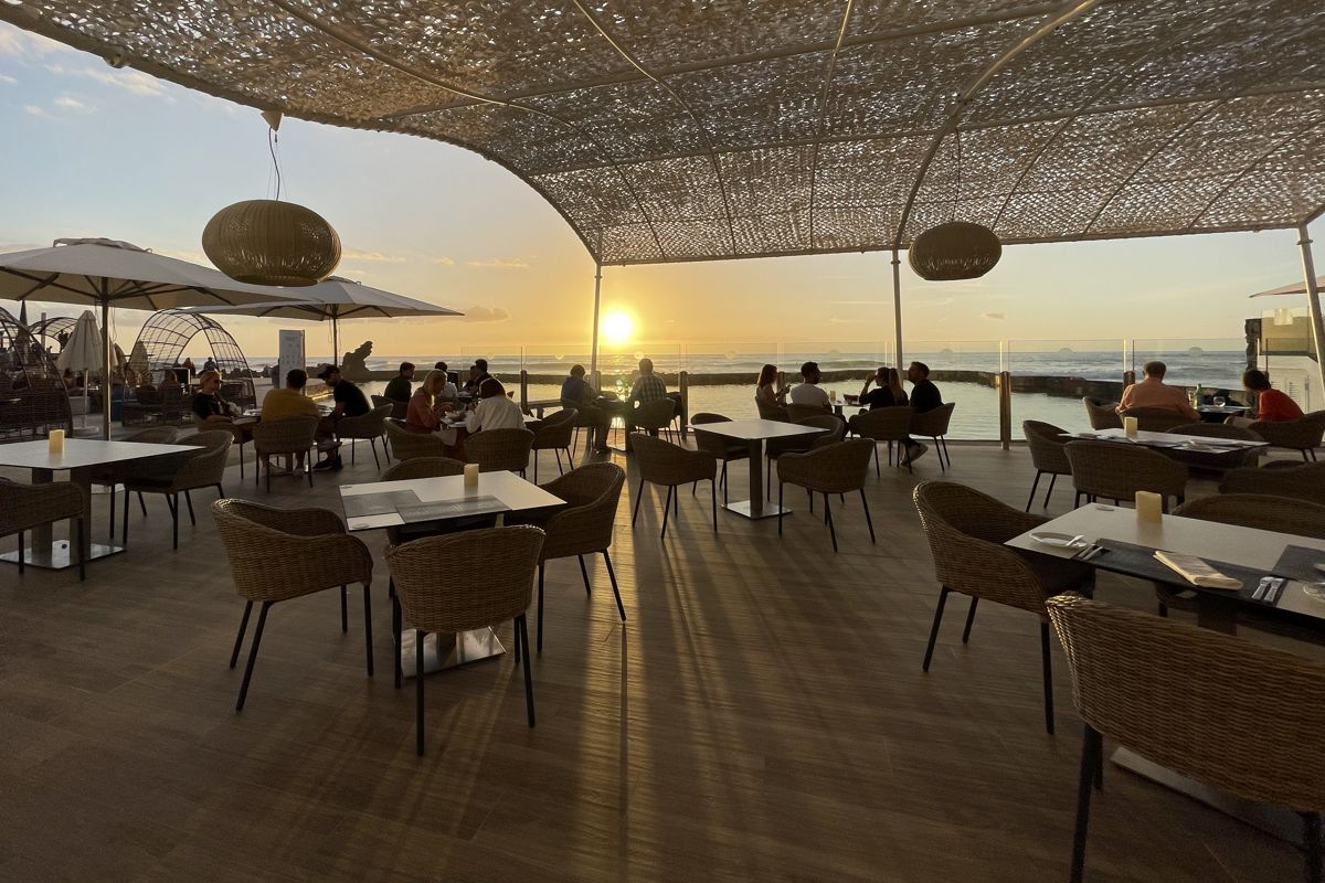Mensen die bij zonsondergang dineren op een terras met uitzicht op zee op Tenerife.