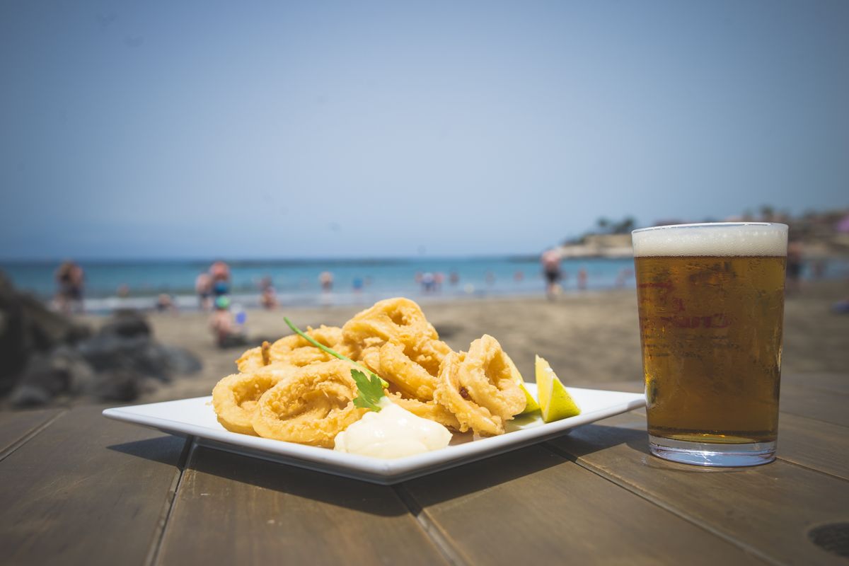Gefrituurde inktvis met citroen en bier op het strand van Adeje, Tenerife.