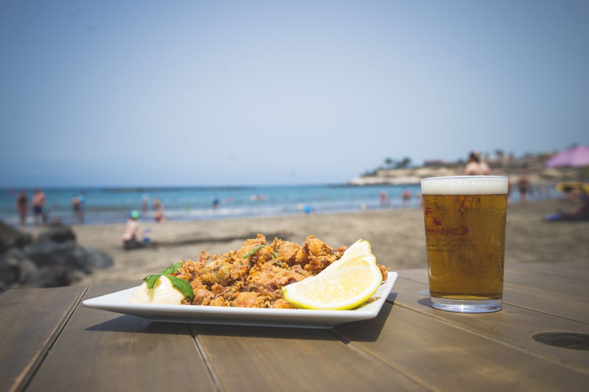 Bord met eten en glas drankje op een tafel op een strand op Tenerife.