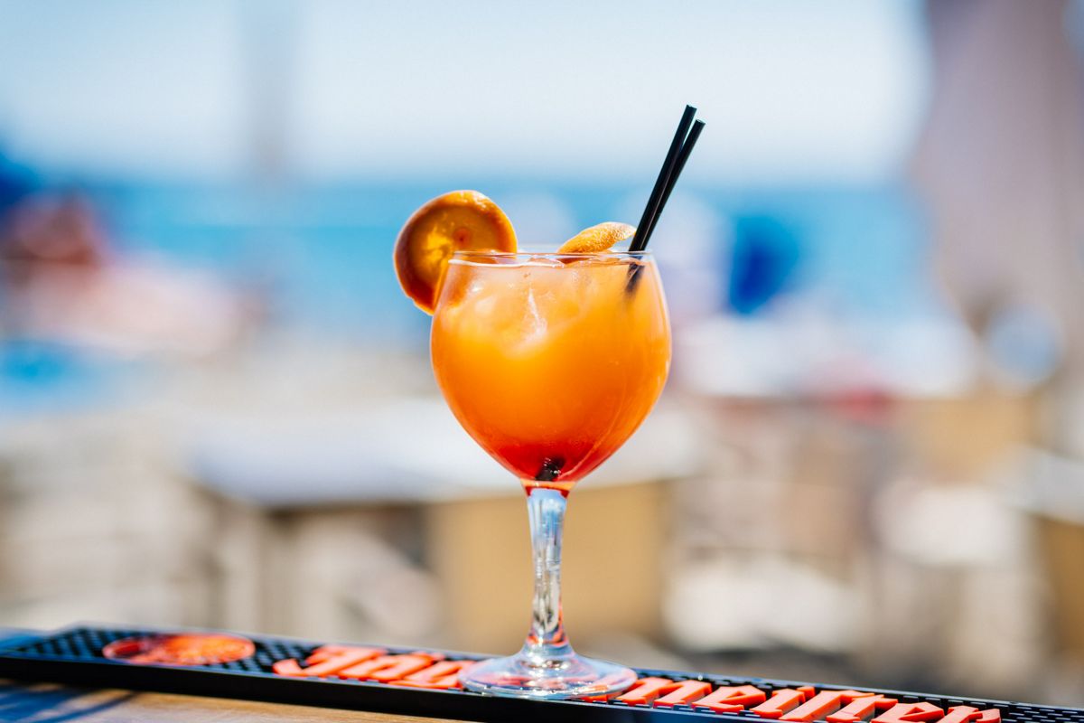 Cocktail met een sinaasappelschijfje en twee zwarte rietjes in een bar op Tenerife.
