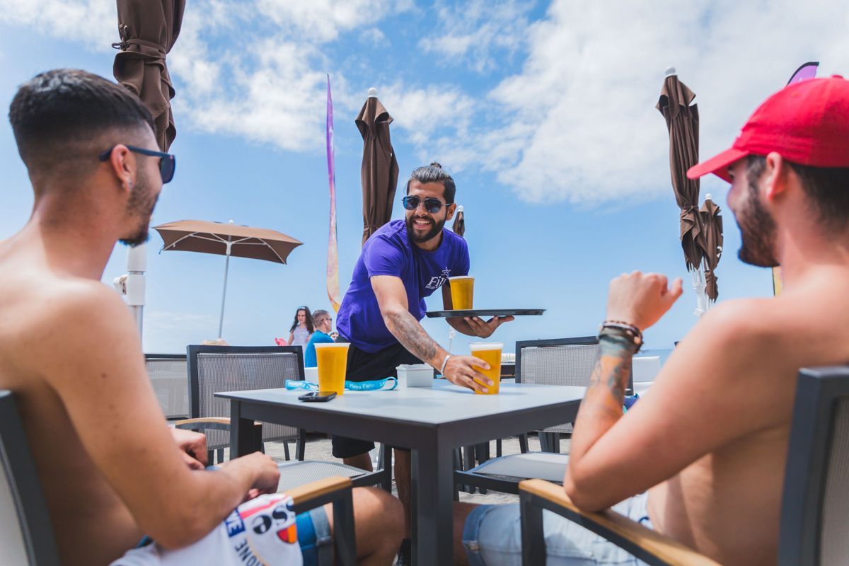 Ober die bier serveert aan twee mannen op een terras op Tenerife.