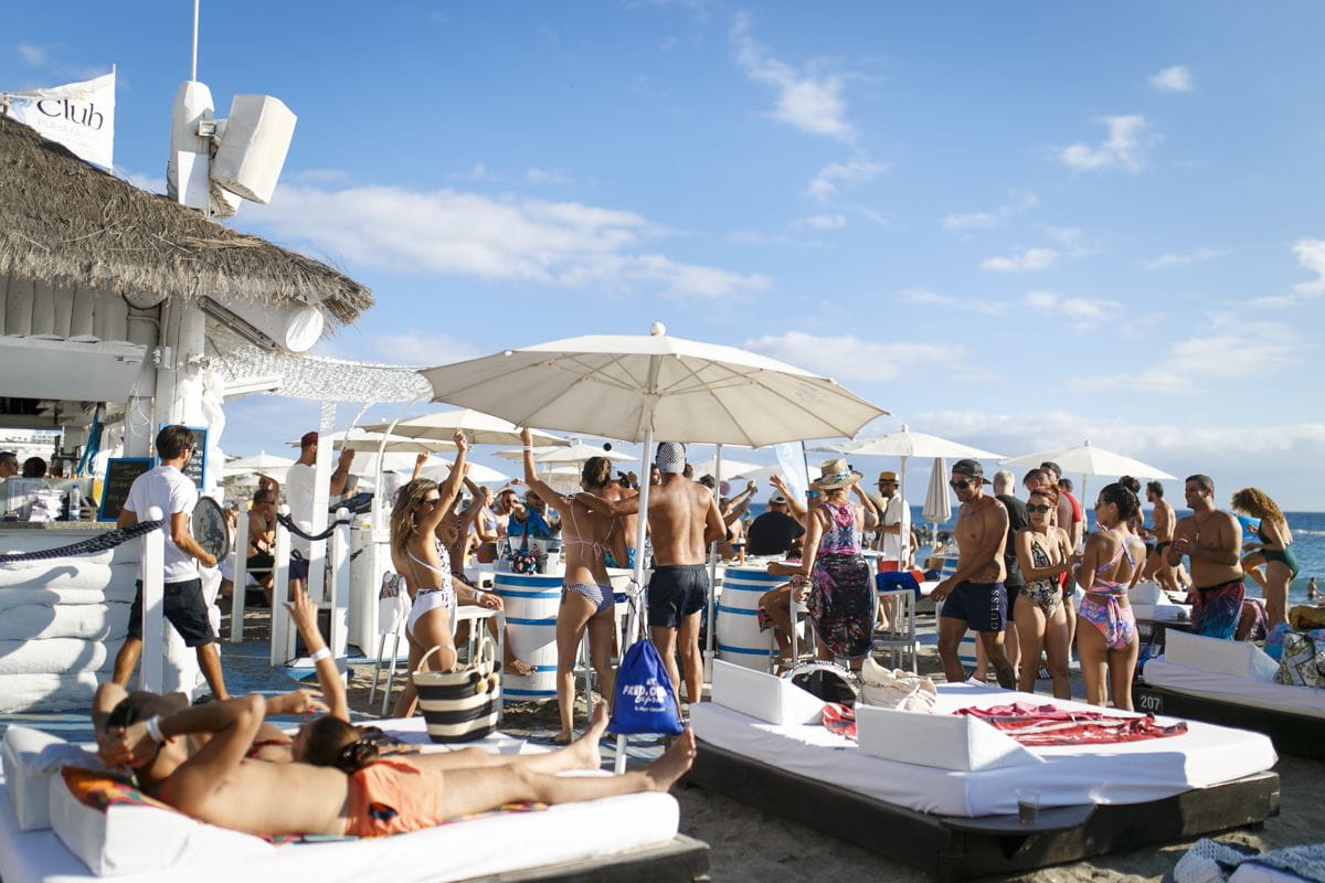 Mensen die genieten van een strandclub op Tenerife onder parasols.