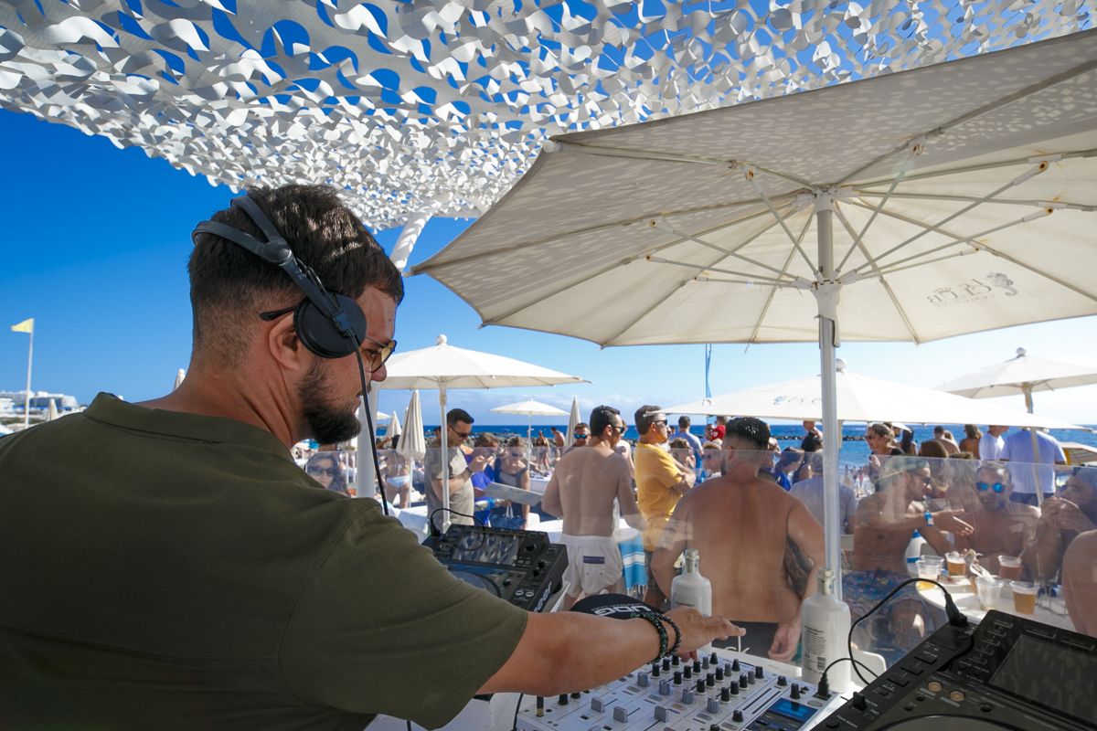 DJ op een openlucht-evenement op het strand van Tenerife met een publiek dat zich vermaakt.