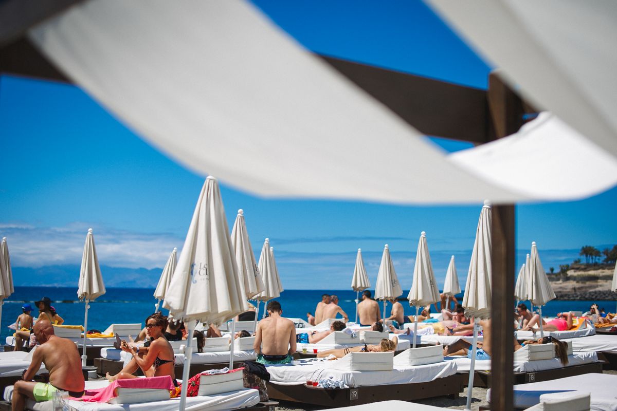 Mensen die in hangmatten zonnebaden onder parasols op het strand van Tenerife.
