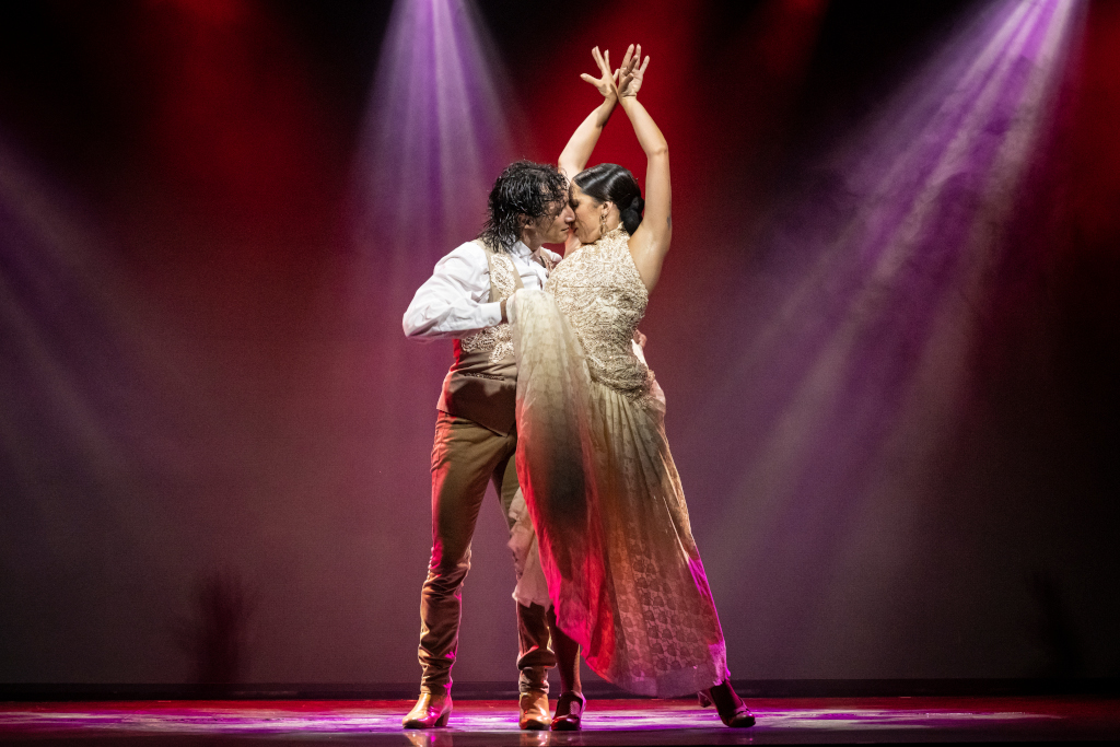 Stel dansend flamenco onder fel licht op een podium.