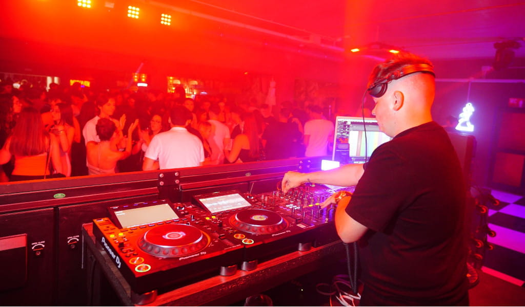 DJ animeerde feest in een nachtclub op Tenerife met rode lichten en dansend publiek.