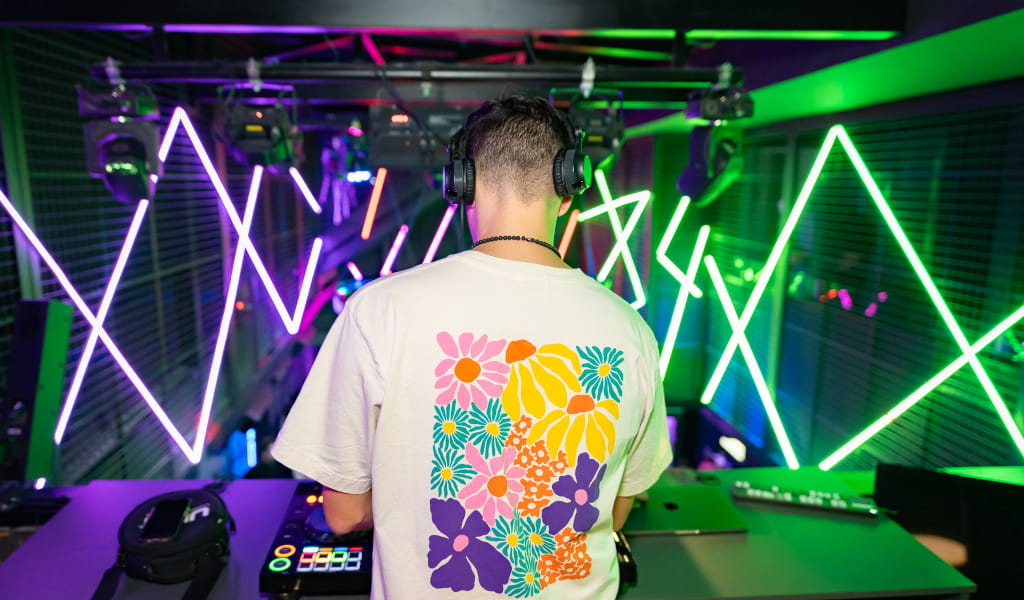DJ in een bloemen-t-shirt mixt muziek in de club op Tenerife met neonlichten.