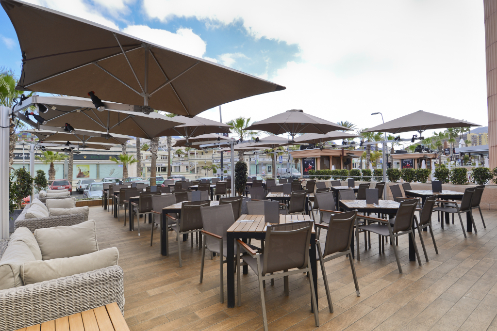 Terras met tafels en stoelen onder parasols in het winkelcentrum van Tenerife.