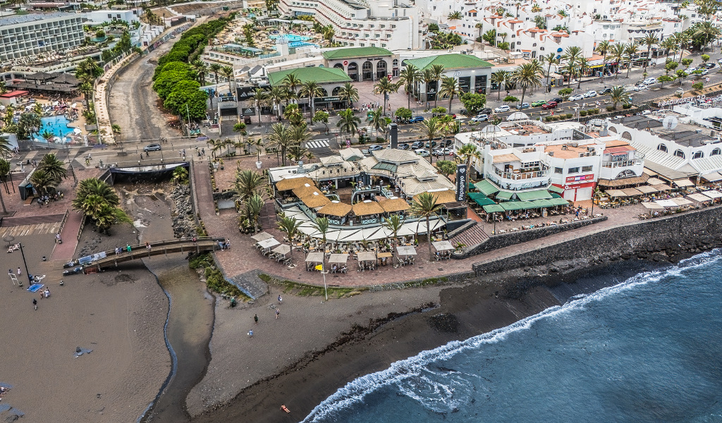 Luchtfoto van het strand en het stedelijke gebied op Tenerife met gebouwen en restaurants in de buurt.