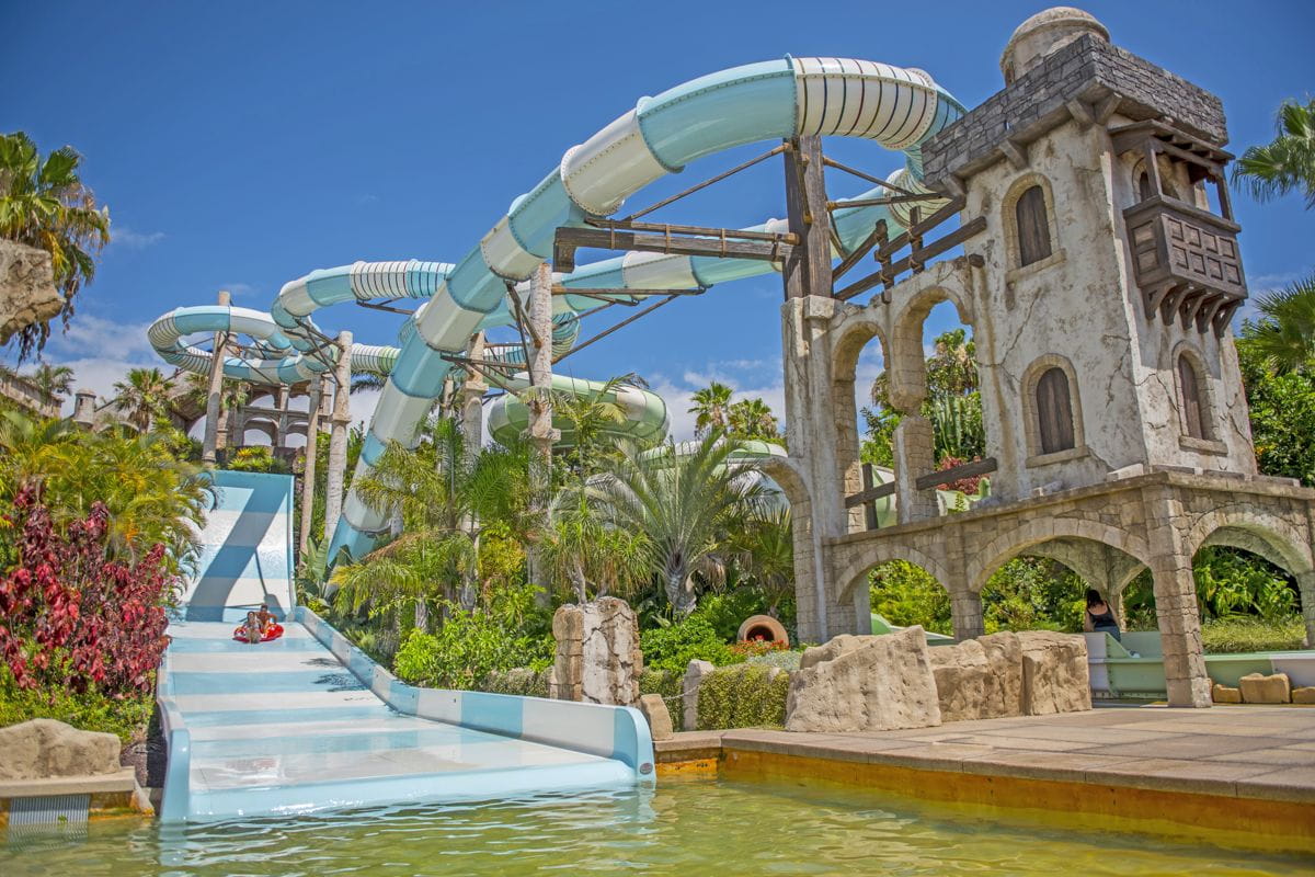 Waterglijbaan in Tenerife pretpark met tropische vegetatie.