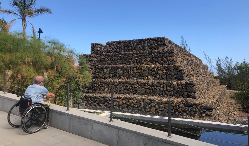 Persoon in een rolstoel die naar een piramide kijkt in Güímar, Tenerife.