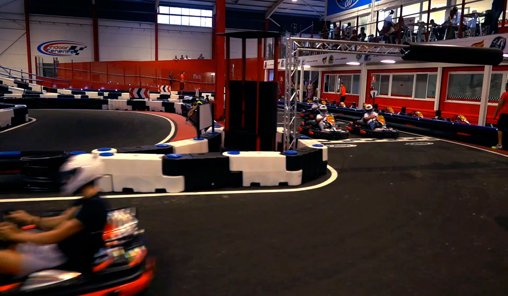 Karts racen op het indoorcircuit van Tenerife met toeschouwers op de achtergrond.