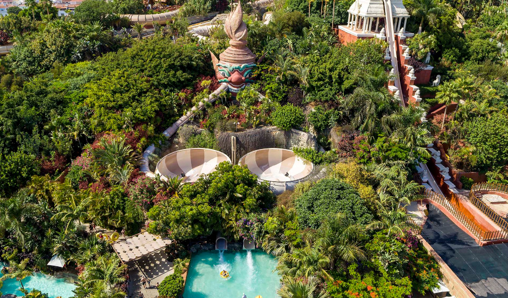 Luchtfoto van het waterpark Siam Park op Tenerife met glijbanen en weelderige begroeiing.