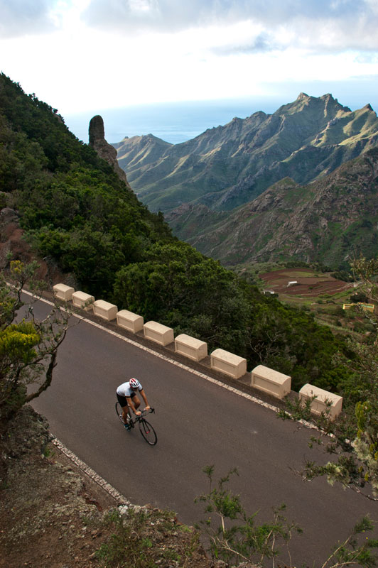 Fietser op bergweg in Anaga, Tenerife, met uitzicht op zee en bergen.