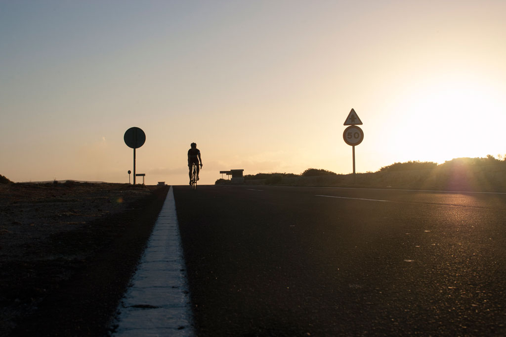 Fietser bij zonsondergang op de weg op Tenerife met een limiet van 50 meter.