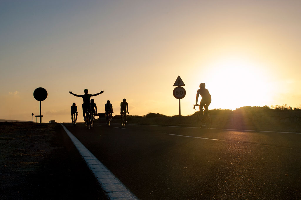 Fietsers op de weg bij zonsondergang op Tenerife, naast een snelheidsbord 50.