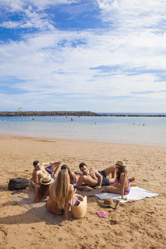 Vriendengroep op het strand van Las Teresitas, Tenerife, genietend van de zon.