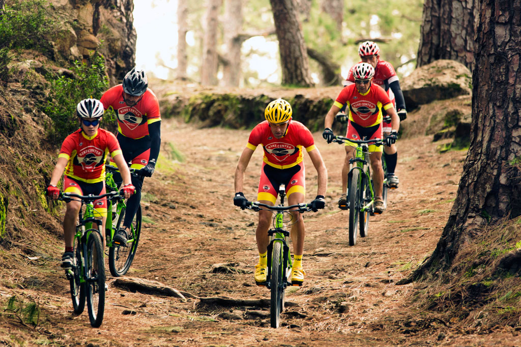 Fietsers op een bosroute op Tenerife in rode en zwarte uniformen.