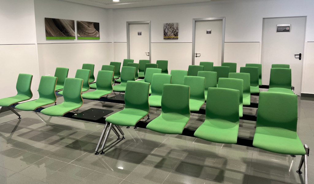Wachtruimte met groene stoelen op Tenerife. Deuren en foto's aan de muur.