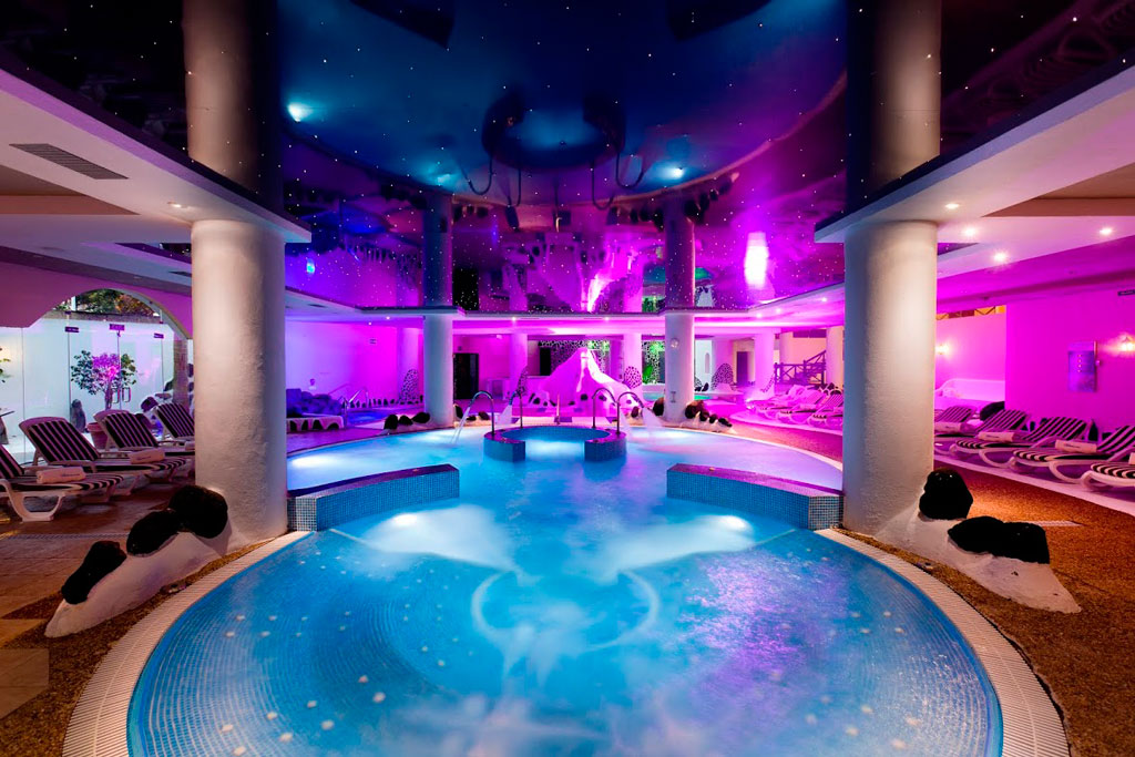 Verlicht binnenzwembad in de spa van Tenerife met ligstoelen overal.