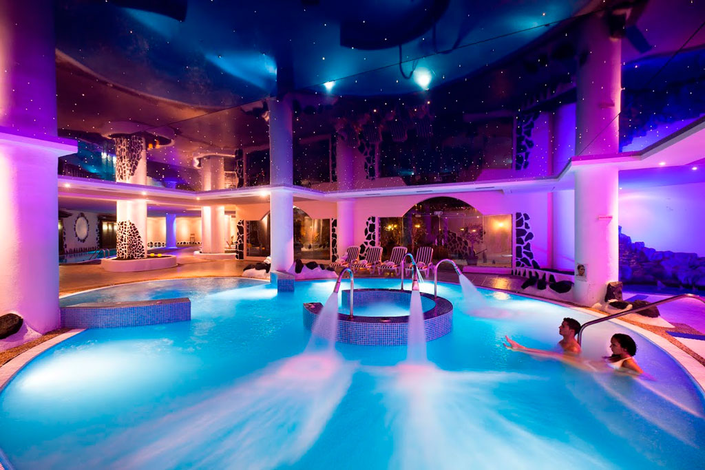 Verlicht binnenzwembad in een spa op Tenerife met twee mensen die ontspannen.