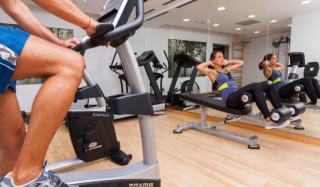 Persoon op hometrainer en vrouw die sit-ups doet in de sportschool op Tenerife.