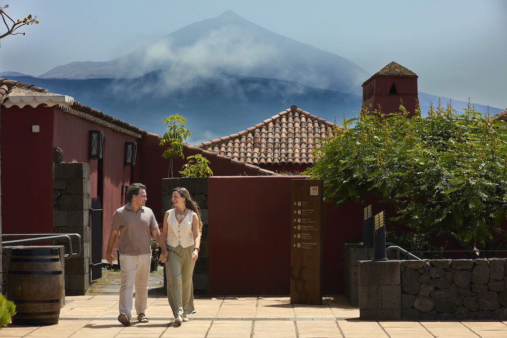 Mensen die bij traditionele huizen lopen met de berg Teide op de achtergrond op Tenerife.