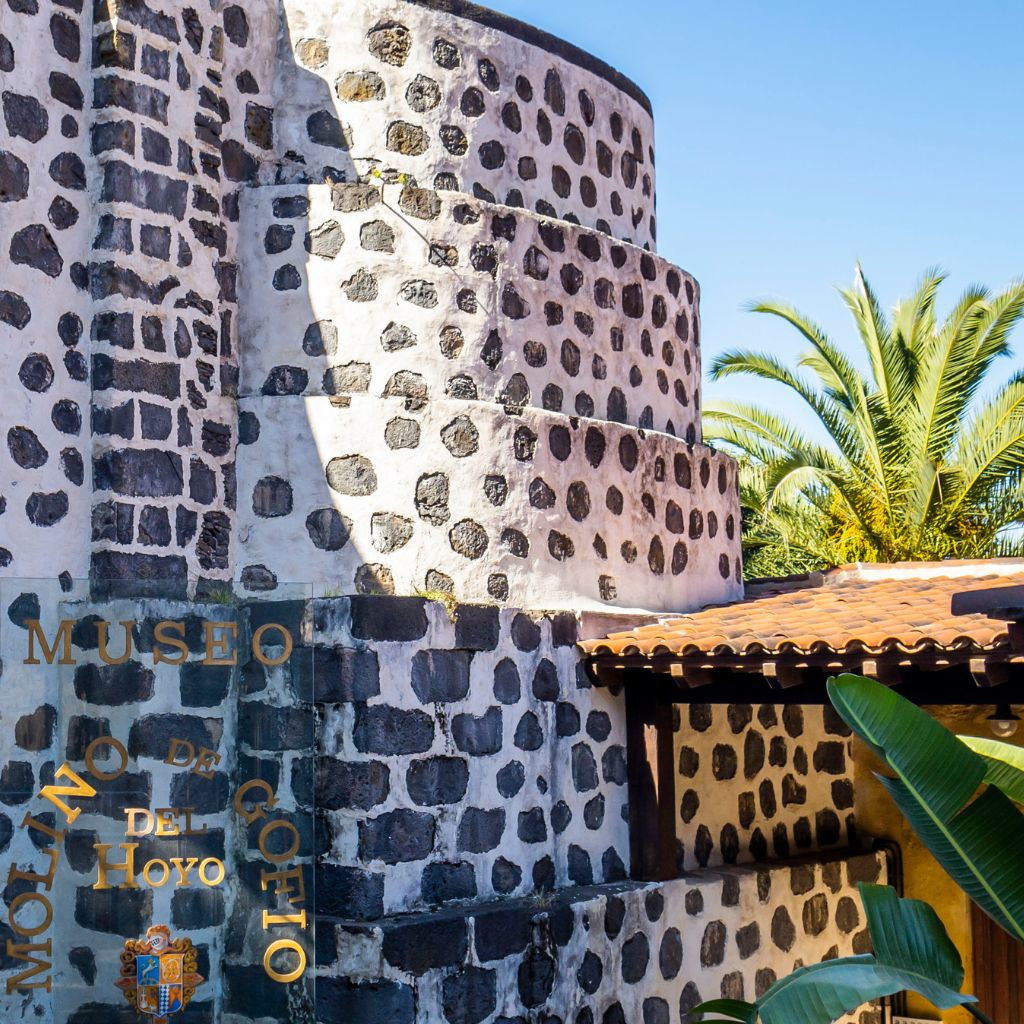 Gofio del Hoyo-molen op Tenerife met palmbomen op de achtergrond.