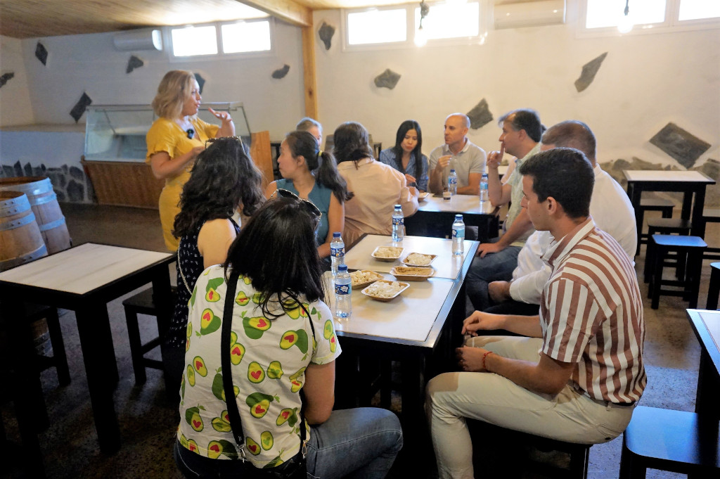 Groep mensen verzamelde zich in een wijnmakerij op Tenerife en deelde eten rond tafels.