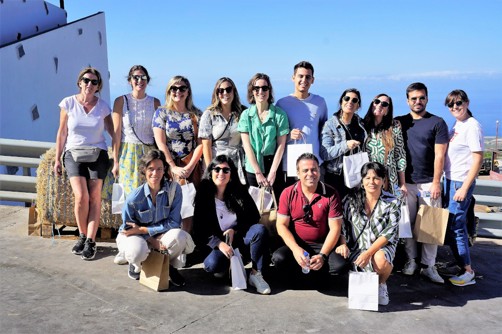 Groep glimlachende mensen voor de zee op een plek op Tenerife, met cadeauzakjes.