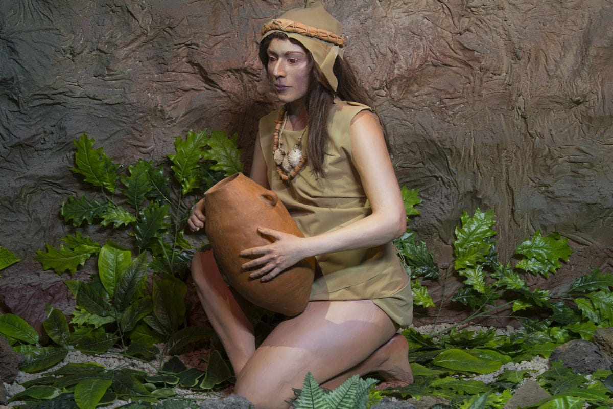 Vrouw in traditionele Aboriginal-kleding die een kleipot vasthoudt op Tenerife.