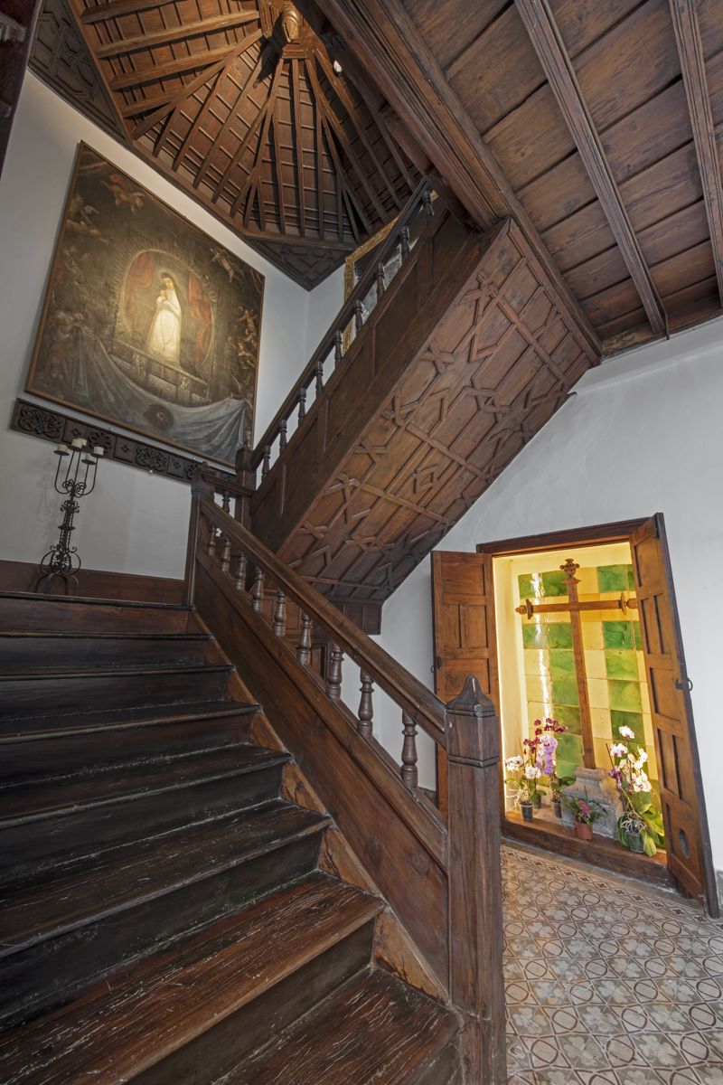 Houten trap met religieuze schildering en glas-in-loodraam in een huis op Tenerife.