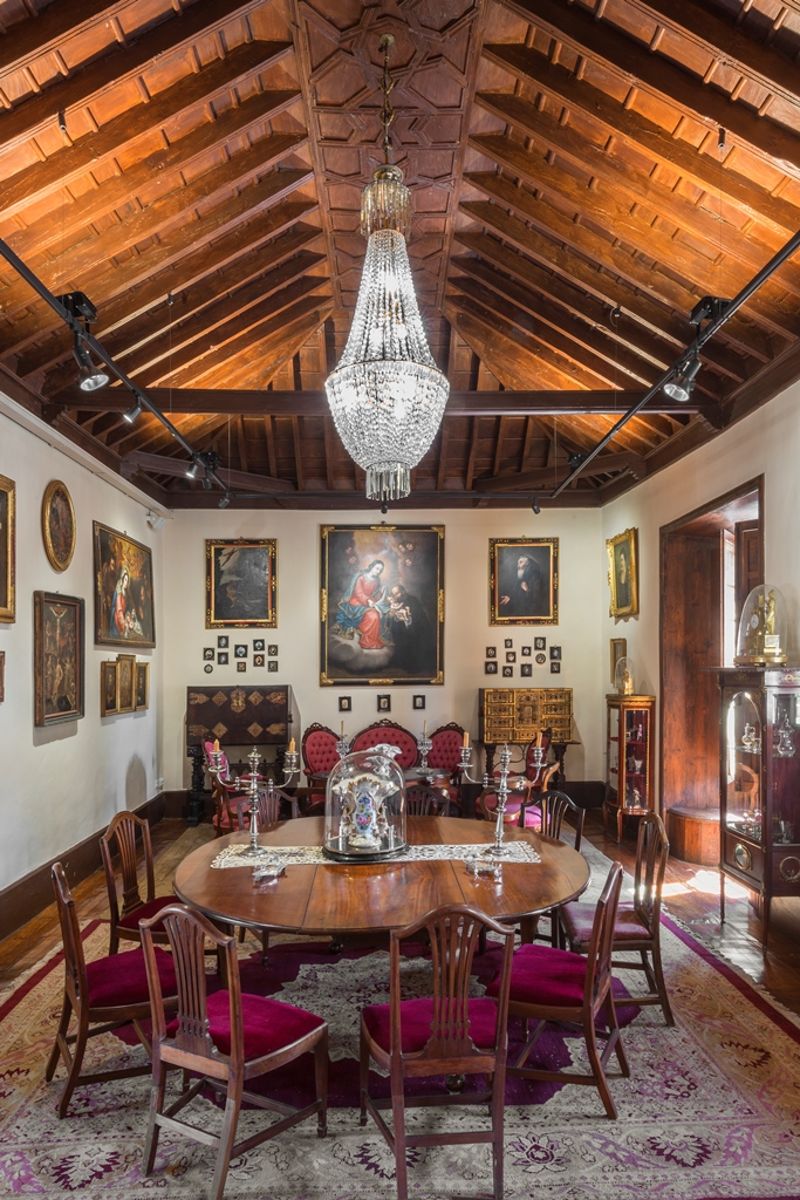 Eetkamer met kroonluchters, ronde tafel en houten plafond, op Tenerife.