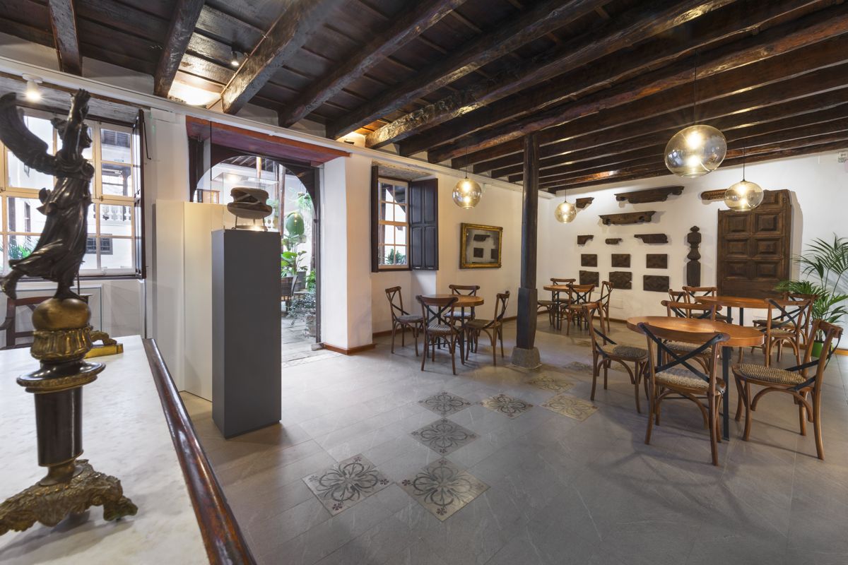 Interieur van een historisch café op Tenerife met houten tafels en klassieke decoratie.